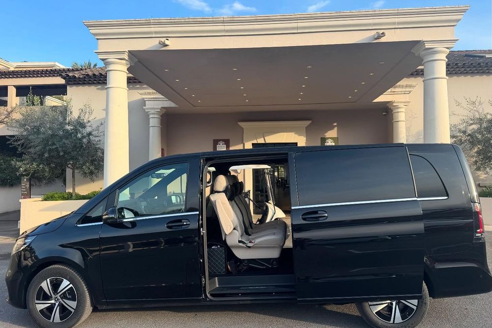 Black premium van with its side door open at a hotel entrance